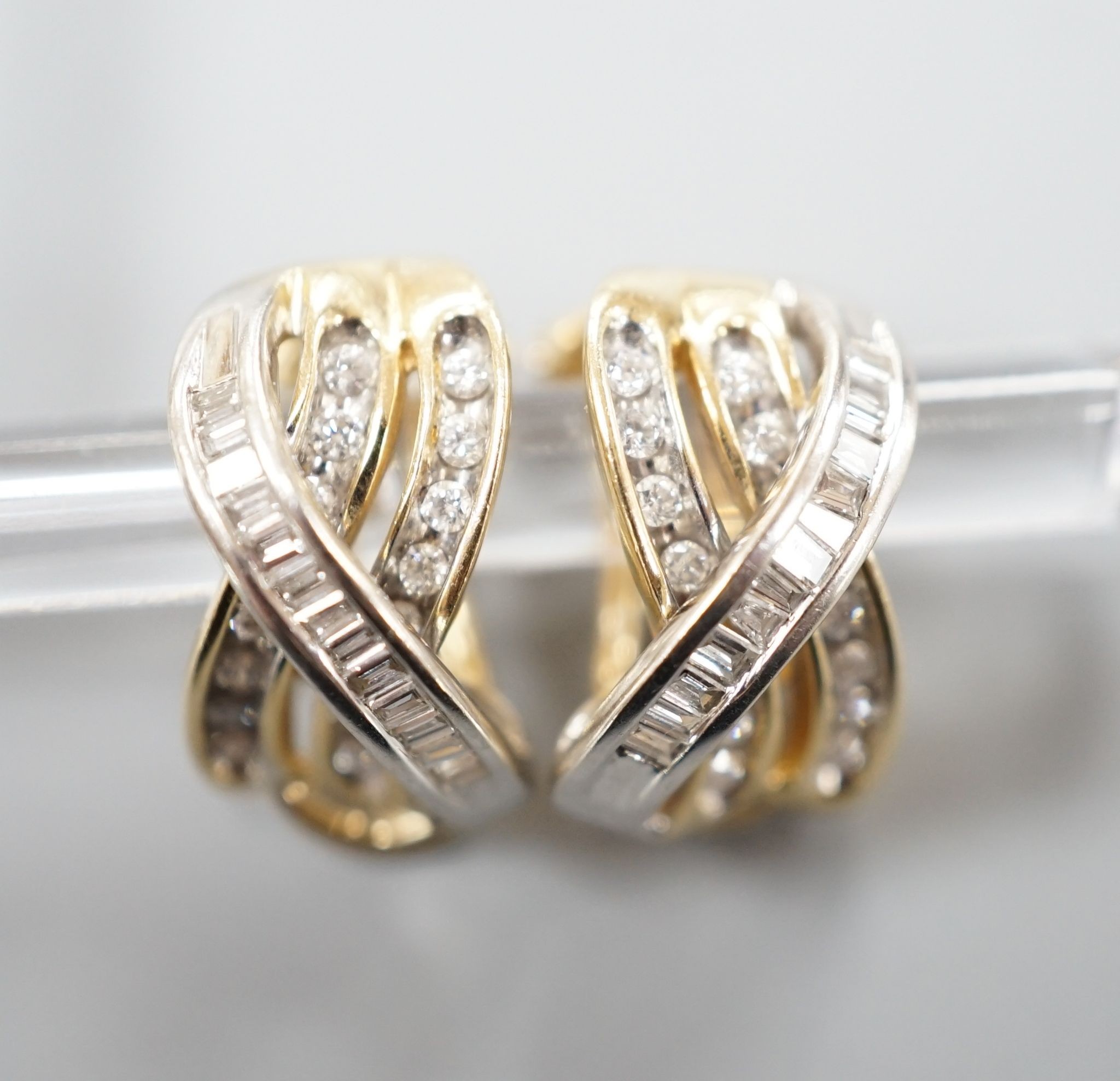 A modern pair of 14k, round and baguette cut diamond set triple row crossover earrings